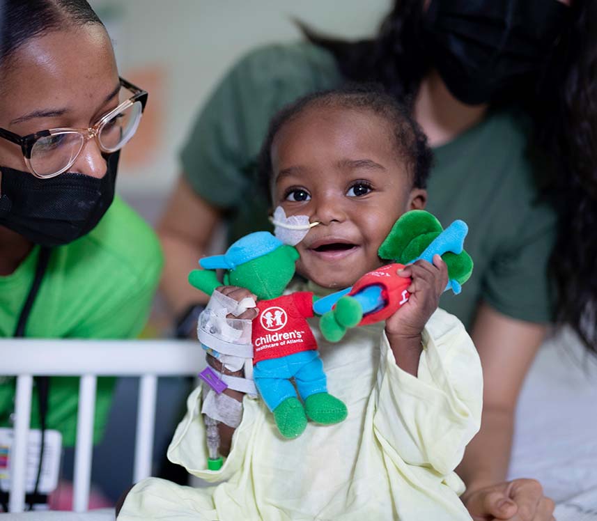 Little girl holding dolls with nurse in pediatric hospital
