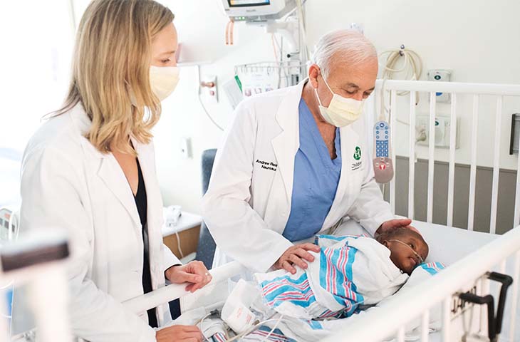 Doctors looking upon a baby in a crib in the hospital