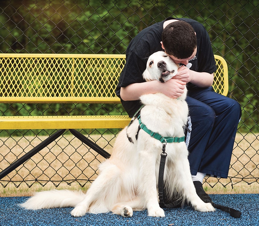 teen brain health patient hugs a therapy dog in the park