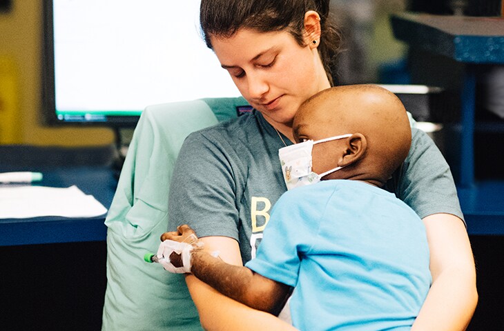 pediatric cancer patient in nurses lap after chemotherapy