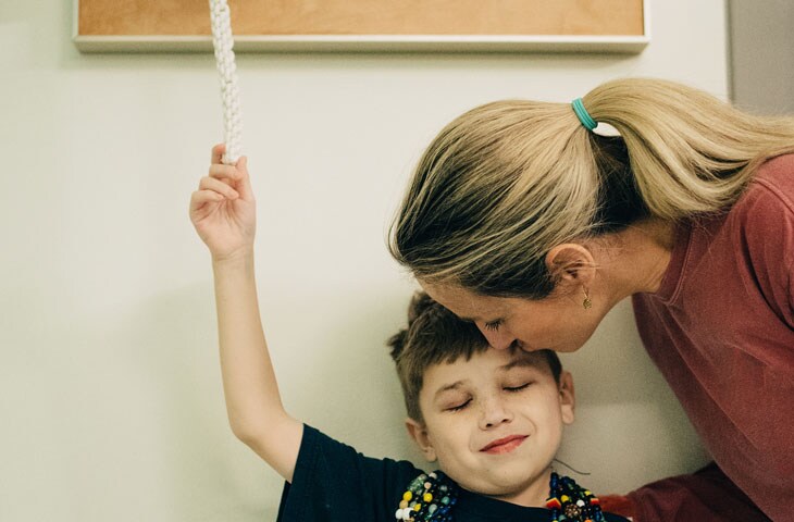 Young boy ringing bell at pediatric hospital marking the end of cancer treatment