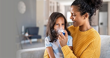 Mom giving daughter breathing treatment for asthma