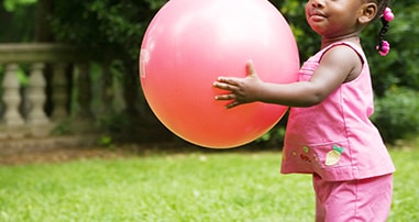 little girl with sickle cell disease holding pink bouncy ball