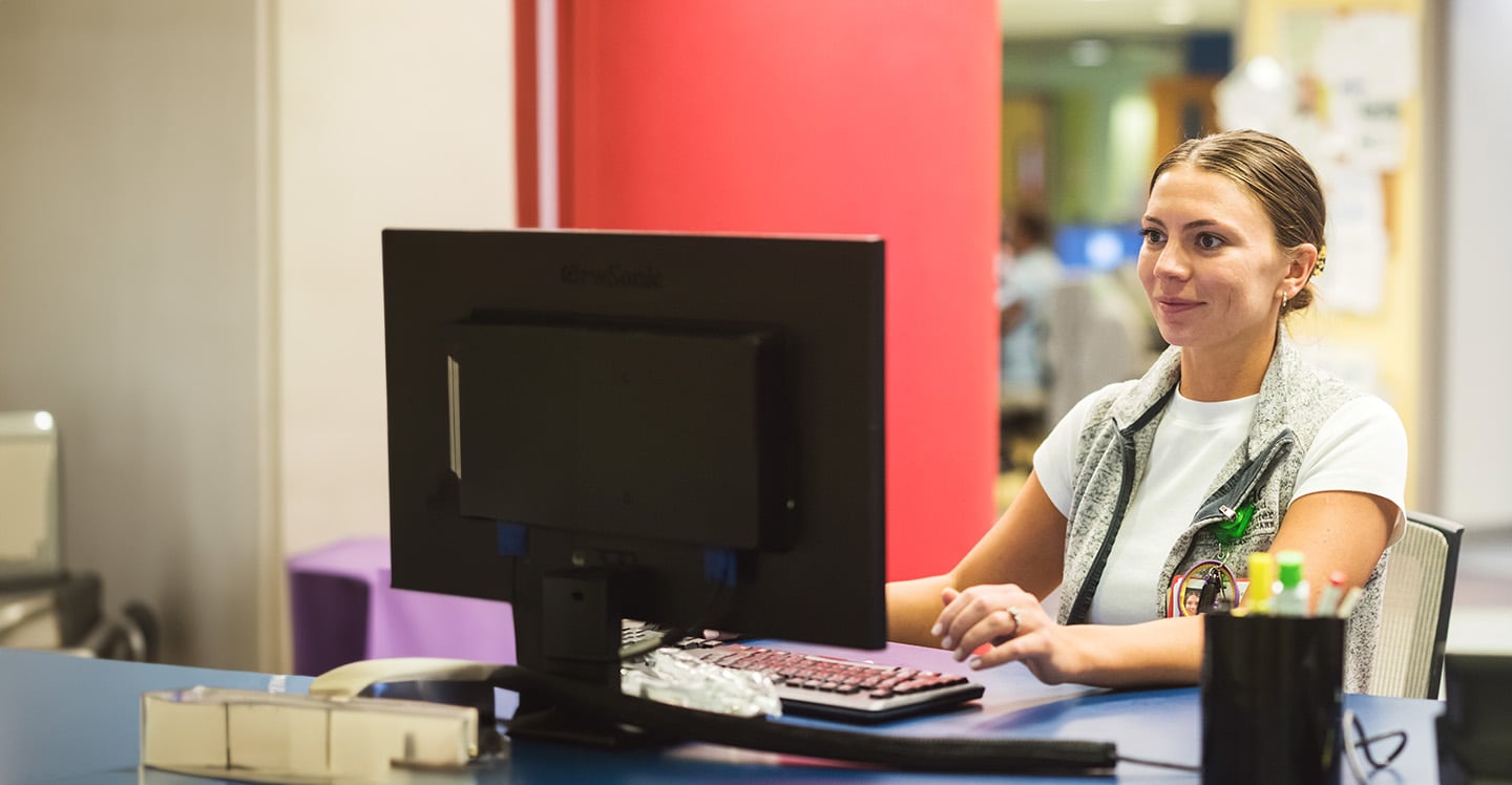Aflac nurse sitting at nursing station on computer.