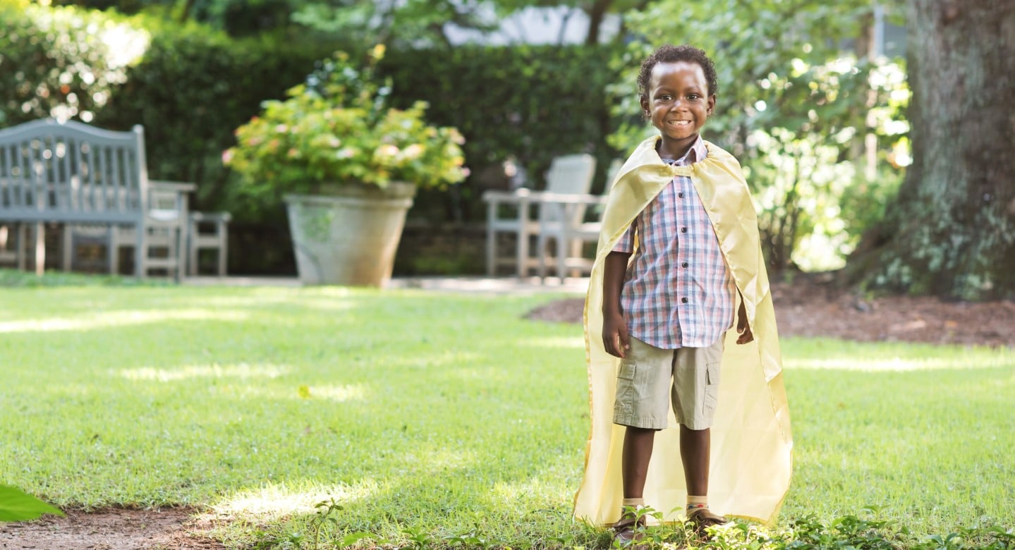 boy smiling wearing cape in pediatric garden hospital